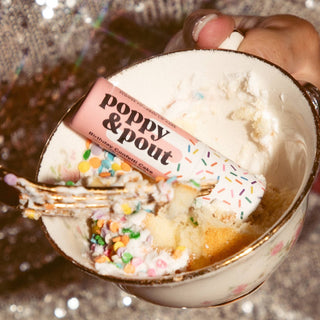 Ice cream with a spoon and 'Poppy & Pout' packaging in a mug.