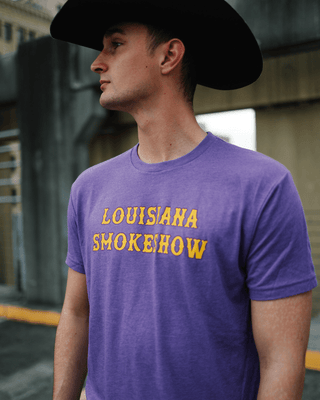 Man wearing a purple t-shirt with 'Louisiana Smoke Show' text and a cowboy hat.