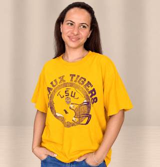 A woman wearing a bright yellow short-sleeve graphic t-shirt with a distressed Geaux Tigers.