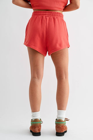 Person wearing coral shorts on a white background