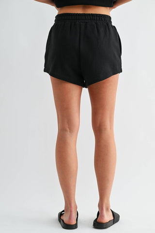 Person wearing black shorts on a plain background