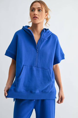 Woman wearing a blue hoodie and pants on a light gray background