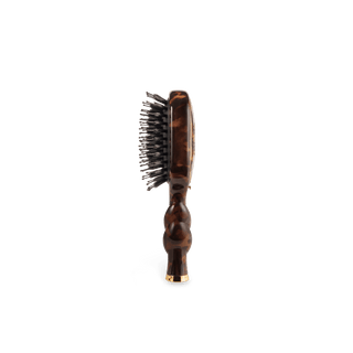 A single oval-shaped hairbrush shown from the side against a plain white background. The brush has a glossy dark brown tortoiseshell-patterned handle and head, black bristles, and a small gold-toned metal accent at the base.