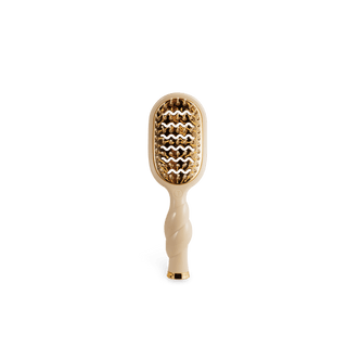 Beige hairbrush with gold bristle head on a white background