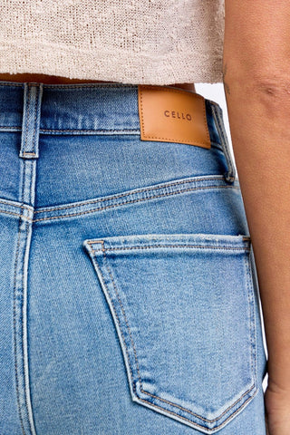 Close-up of blue jeans with a Cello brand label on the pocket.