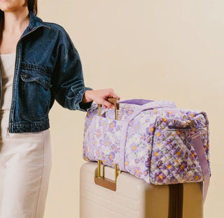 On-The-Go Quilted Weekender Bag in Bouquet Beauty Purple carried over a suitcase
