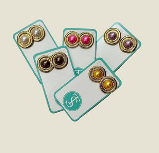 Set of gold and colored gemstone earrings on display cards with a visible brand logo.