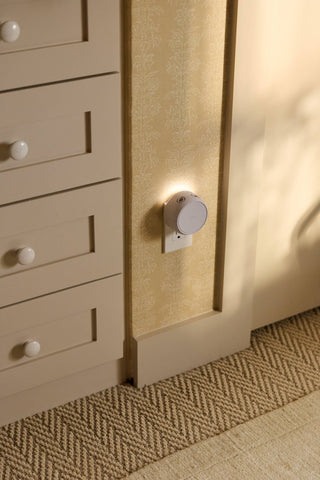 Close-up of a beige cabinet with drawers and a light fixture on a textured wall.