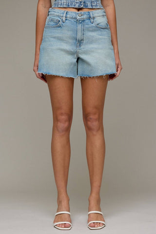 Light blue denim shorts worn by a person on a plain background