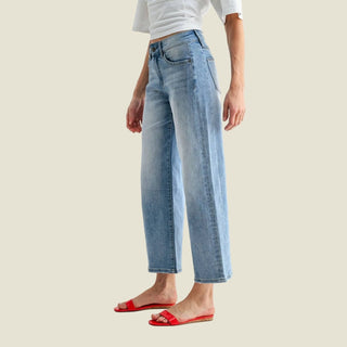 Person wearing light blue jeans and red sandals on a white background