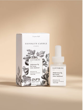Brooklyn Candle Studio Santorini fragrance oil shown with its white product box and a small clear dropper bottle on a warm beige studio background.