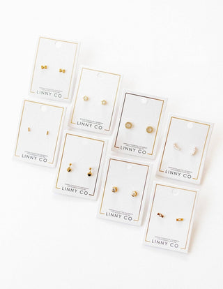 Set of gold earrings on LINNY CO branded cards against a white background