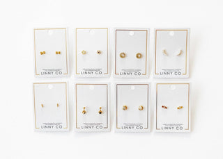 Set of gold earrings on LINNY CO branded cards against a white background