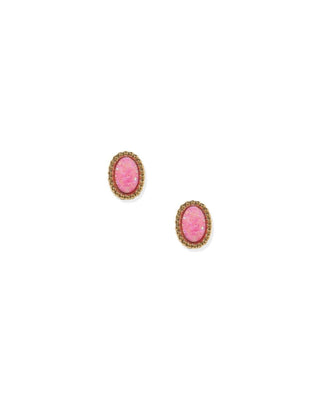A pair of oval stud earrings featuring textured pink cabochon stones set in a gold-toned, beaded halo border, shown on a plain white background.