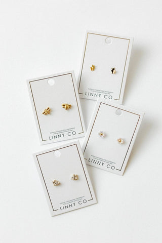Gold earrings on LINNY CO branded cards against a white background