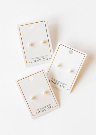 Three pairs of earrings in packaging with 'LINNY CO' branding on a white background