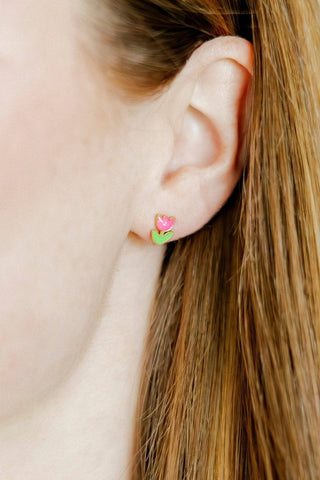 Close-up of an ear wearing a pink and green floral stud earring.