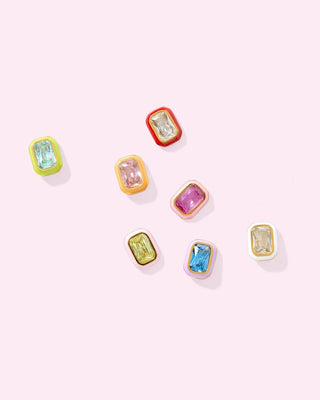 Set of colorful gemstone earrings on a light pink background