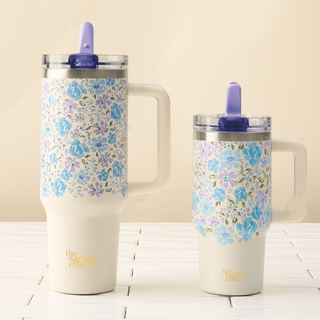 Two floral-patterned tumblers with handles on a wooden surface.