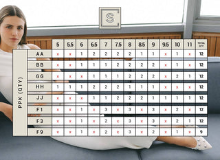 Person holding a large grid chart with various letters and numbers, sitting on a couch.