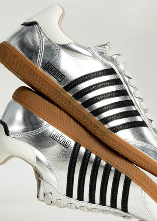 Silver sneakers with black stripes and brown soles on a white background