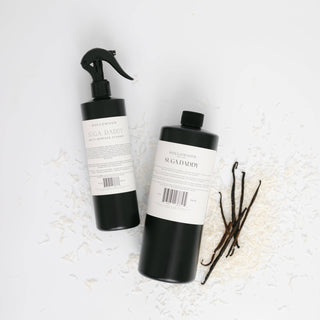 Two black bottles with white labels on a textured white surface.