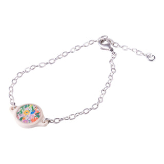A silver chain bracelet with a small oval charm featuring a colorful floral illustration, set against a plain white background.