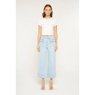 Woman wearing light blue jeans and a white top on a white background