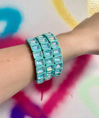 Turquoise beaded bracelet on a wrist with a colorful abstract background
