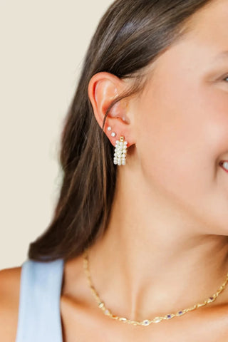 Close-up of a person wearing pearl earrings with a colorful blurred background