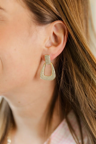 Close-up of a person wearing a gold hoop earring with a blurred background