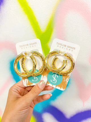 Raya Hoops – gold hoop earrings held in hand