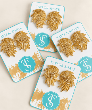 Four pairs of gold beaded fan-shaped earrings displayed on white backing cards with turquoise borders and the brand name Taylor Shaye.