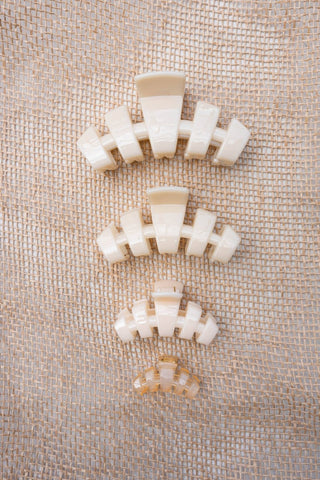 Set of white hair clips on a textured beige fabric background