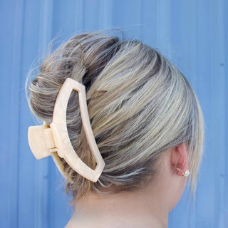 Person with a stylish hairdo featuring a large beige hair clip against a blue background