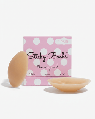 A pink polka-dot box labeled 'Sticky Boobs the original' with two flesh-toned adhesive breast forms shown in front on a clean white background.