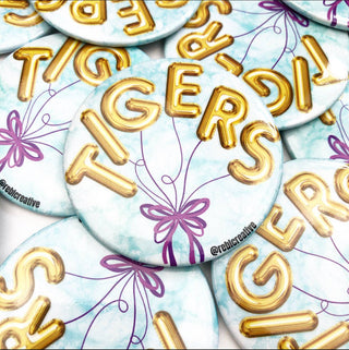 Buttons with 'TIGERS' in gold letters on a light blue background with decorative elements.