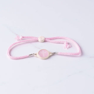 Pink bracelet with a heart-shaped charm on a light purple background