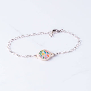 Silver bracelet with a floral charm on a light purple background