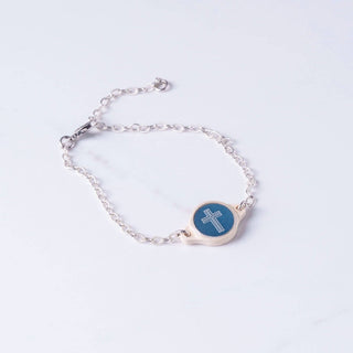 Silver bracelet with a blue circular charm featuring a cross on a light gray background