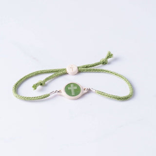 Green bracelet with a cross charm on a light gray background