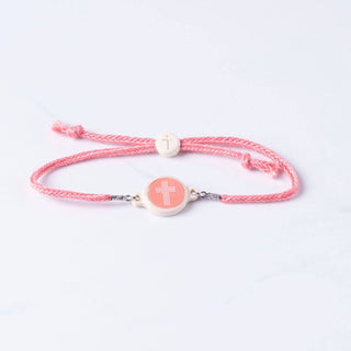 Pink bracelet with a circular charm featuring a cross on a white background