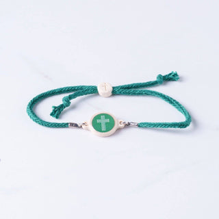 Green braided bracelet with a green circular charm featuring a cross on a white background