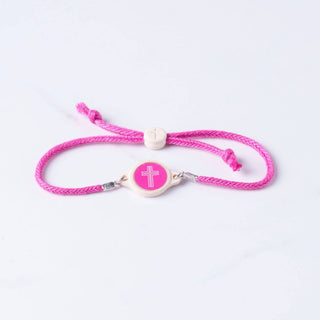 Pink braided bracelet with a white bead and cross charm on a light gray background