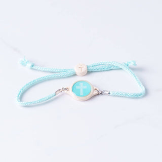 Light blue braided bracelet with a cross charm on a white background