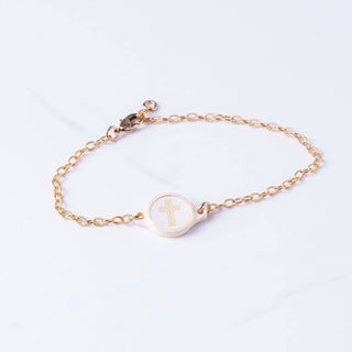 Gold bracelet with a cross charm on a light gray background