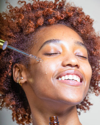 Woman applying a skincare product to her face with a dropper.